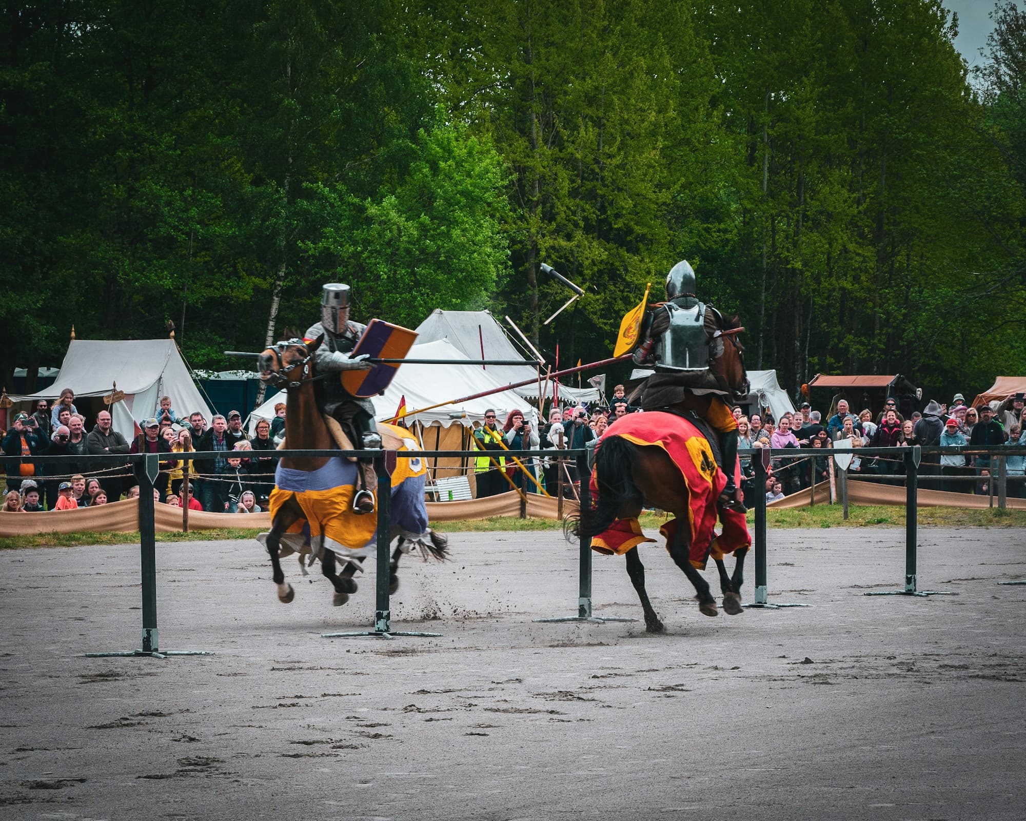 Zwei berittene Ritter beim Tjost, eine Lanze zersplittert vor Zelten und Zuschauern